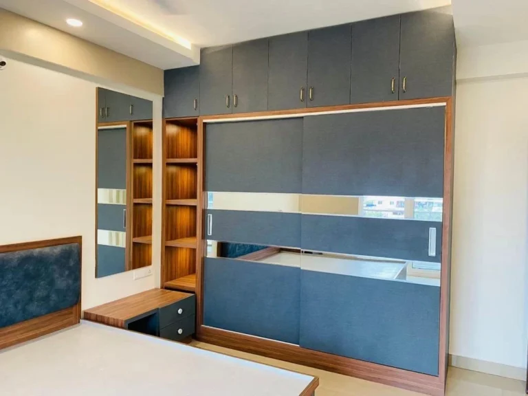 Wardrobe with blue-grey shutters, mirror and open shelf by House Decors, Chennai