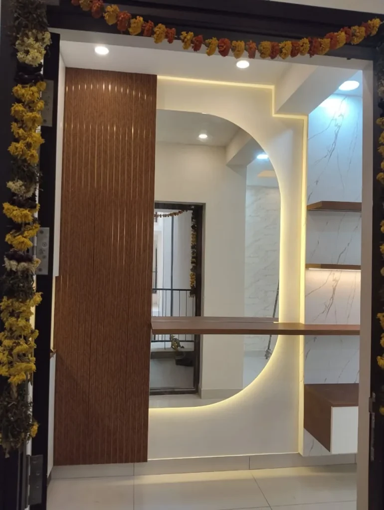 Entry area with a curved LED-lit mirror, wooden fluted panel and marble-look shelves, House Decors, Chennai