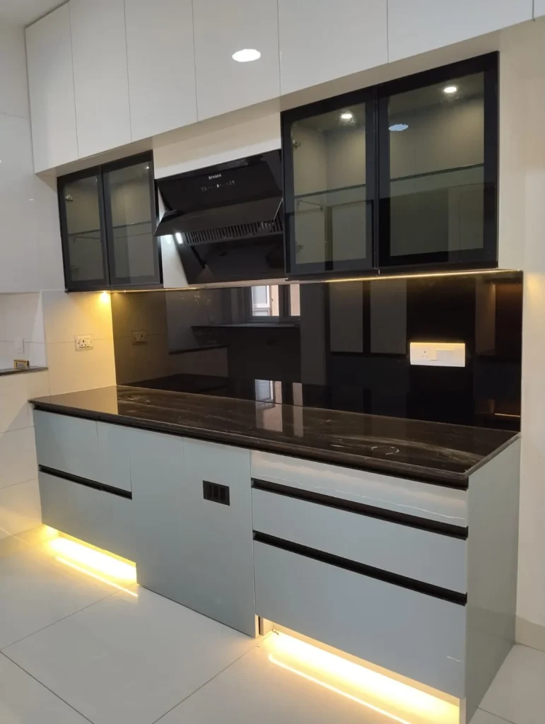 Modular kitchen with black-framed glass wall units, a chimney, black backsplash and grey base drawers with LED lighting, House Decors, Chennai