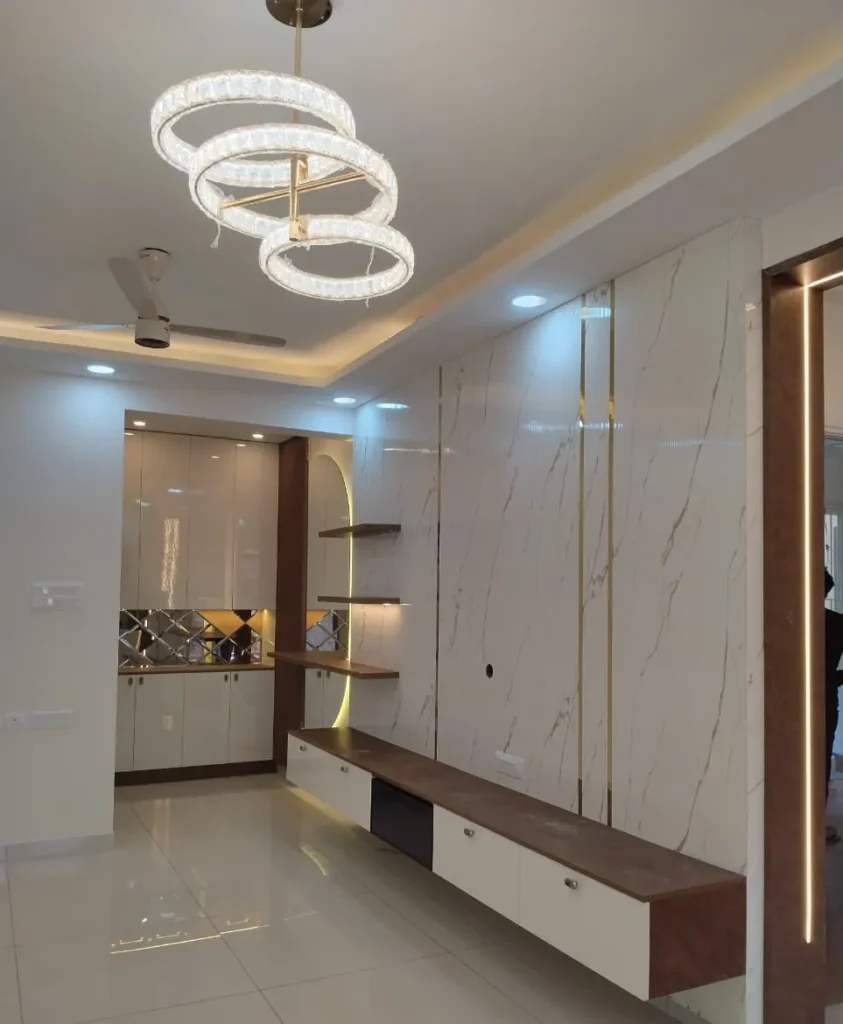 Living room with a ring chandelier, marble-look TV wall with gold strips, a floating TV unit and a crockery unit, House Decors, Chennai