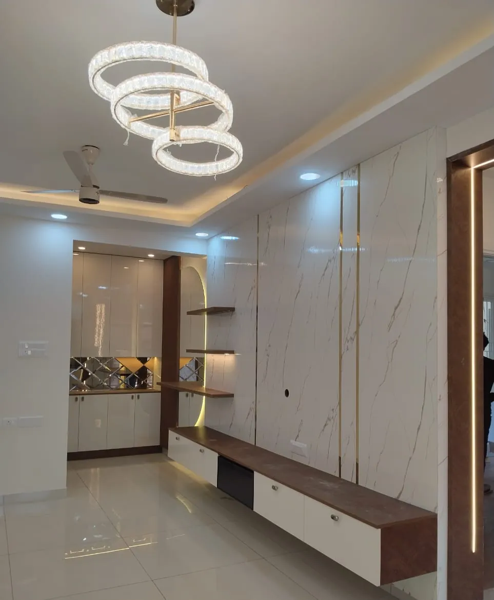 Living room with a ring chandelier, marble-look TV wall with gold strips, a floating TV unit and a crockery unit, House Decors, Chennai