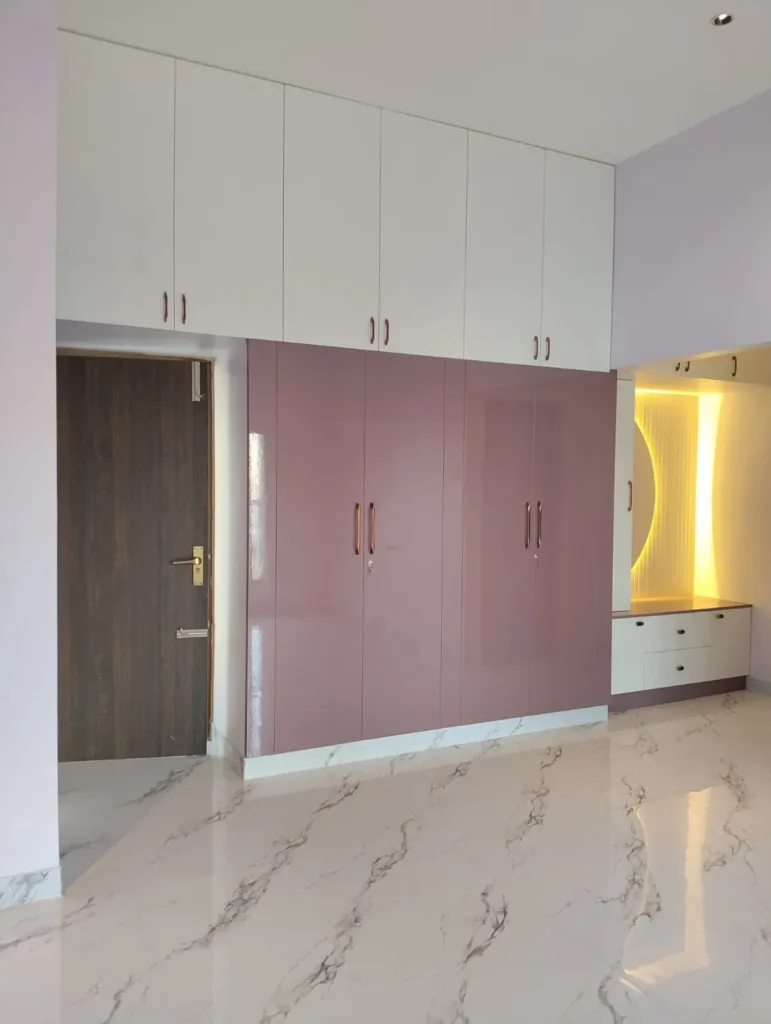 Bedroom wardrobe in mauve gloss with white loft cabinets and a dressing unit with a lit half-moon mirror, House Decors, Chennai