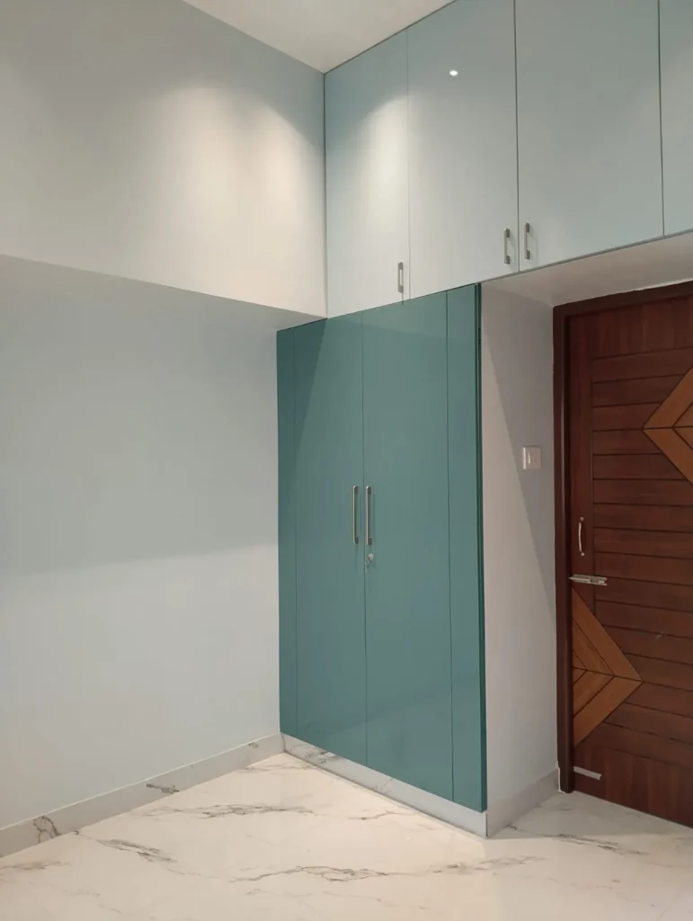 Teal wardrobe with pale blue loft doors beside a patterned wooden door, House Decors, Chennai