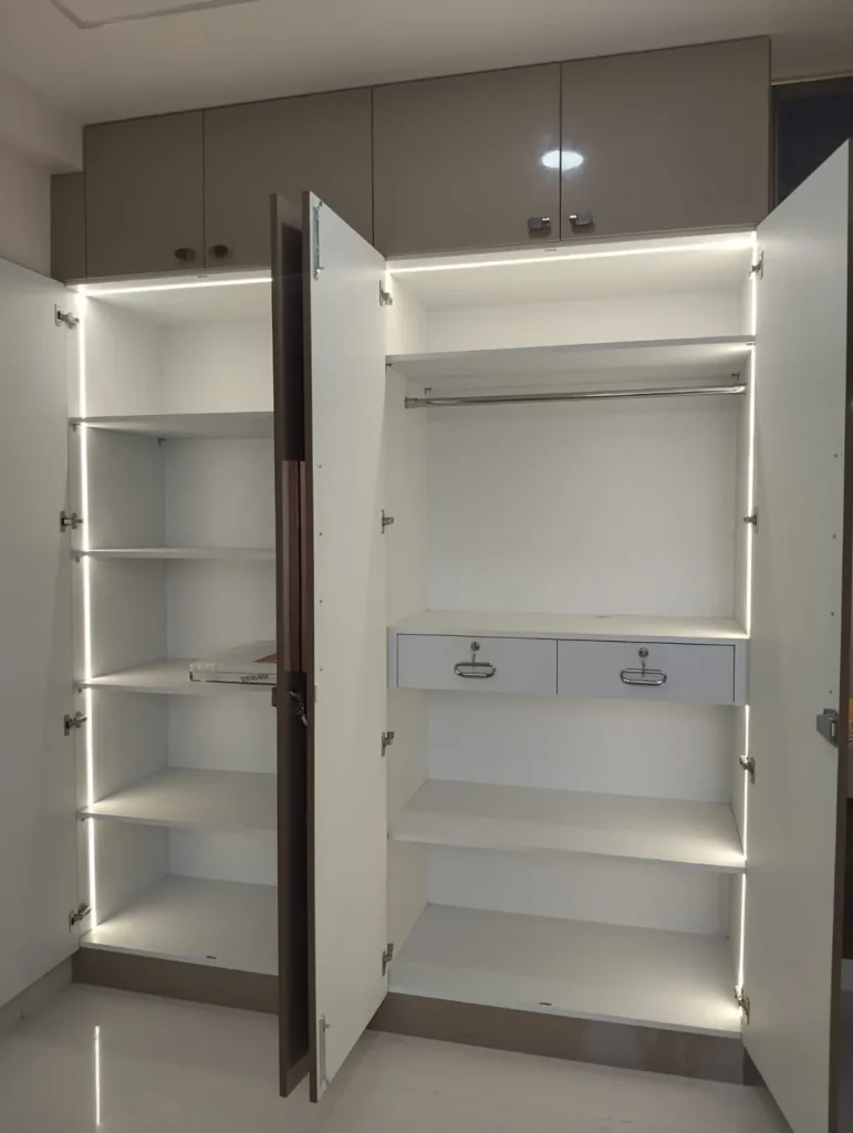 Open wardrobe with LED strips along the shelves, a hanging rail and two drawers with locks, House Decors, Chennai