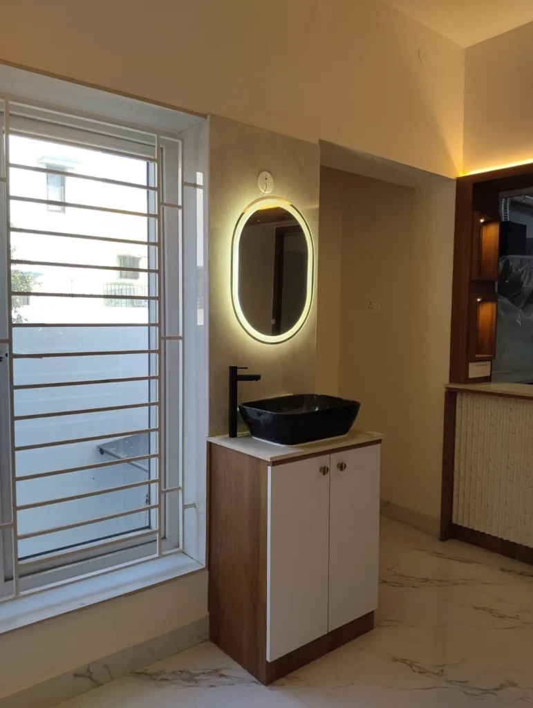 Wash-basin vanity with a black basin, oval LED mirror and a wood and white cabinet, House Decors, Chennai